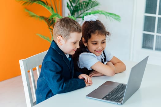 Boy and girl studying at table with laptop at school