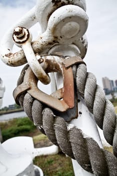 Rustic weathered mooring bollard with heavy-duty rope, showcasing strength and durability in maritime industry. Located in Toledo, Ohio.