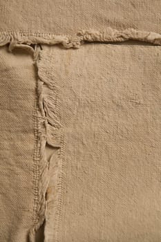 Vintage Beige Textured Fabric with Frayed Seam - A close-up view of a rugged and unfinished canvas or cotton blend fabric. The frayed seam shows individual threads and fibers, adding a rustic touch.