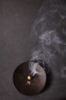 A serene scene from above of incense with wisps of smoke, symbolizing completion and fleeting inspiration.