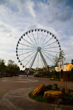 Experience the thrill of a towering Ferris wheel in Gatlinburg, Tennessee's lively leisure park. This iconic landmark offers family-friendly entertainment and breathtaking views against a partly cloudy sky.