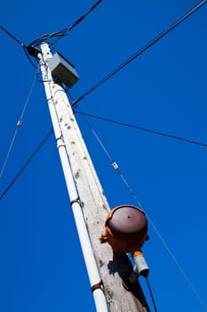 Essential urban infrastructure: A weathered utility pole stands tall against a vibrant blue sky in Empire, Michigan. Highlighting the intricate network of power lines and electrical equipment, this image captures the component of our energy.