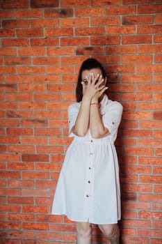 brunette woman in dress covering her face with her hands