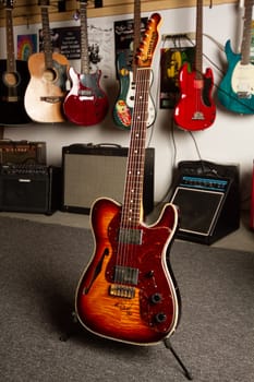 Vibrant music studio showcasing a sunburst electric guitar on a stand, surrounded by a collection of guitars and amplifiers. Perfect for music enthusiasts and publications on instruments and creative spaces.