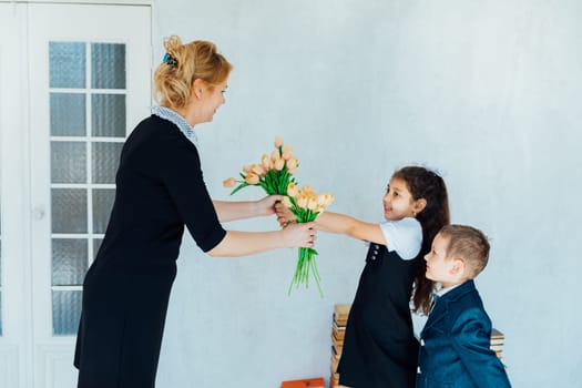 Schoolchildren giving flowers to teacher for holiday
