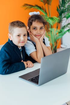Boy and girl studying at table with laptop at school