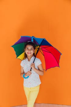 Girl standing under colorful umbrella from rain