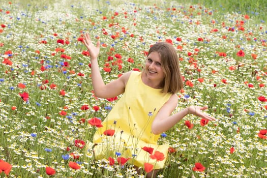 young beautiful caucasian girl sitting in the middle of a blooming field of daisies, cornflowers and poppies happy, free, carefree and smiling, High quality photo