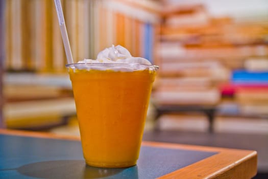 Enjoy a moment of indulgence with our refreshing cold beverage, topped with a dollop of whipped cream. Served in a clear plastic cup with a white straw, this drink is perfect for a relaxing break at your favorite cafe.