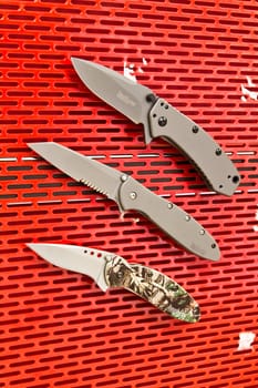 Organized and Versatile: Collection of Folding Knives on Vibrant Pegboard Display. Perfect for Outdoor Gear, Tactical Equipment, and Home Organization.