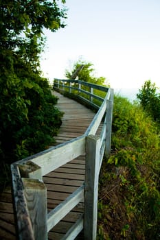 A tranquil wooden boardwalk winds through lush greenery in Empire, Michigan. Explore the peaceful beauty of nature on this serene hiking trail.