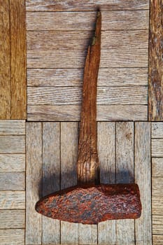 Vintage iron hammer with weathered wooden handle, showcasing rustic craftsmanship against a backdrop of aged planks. Perfect for conveying durability and the passage of time. Ideal for businesses in history, outdoor equipment, or rural lifestyle.