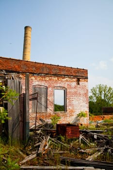 Decay of Industry: A dilapidated factory in Pierceton, Indiana stands as a weathered monument to the past, with a towering brick chimney and crumbling walls. Nature reclaims the abandoned site, creating a mesmerizing blend of ruin and greenery.