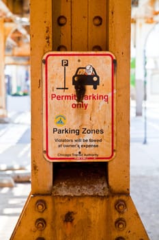 Regulated Urban Parking: Chicago Transit Authoritys Permit Only Zone warns of towing violators amidst a weathered sign and rusty beam in an urban cityscape.