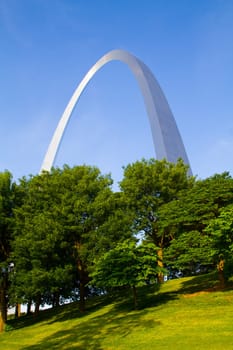 Iconic St. Louis Arch stands tall in lush park, a symbol of human achievement blending harmoniously with natures beauty. Perfect for travel, landmarks, and architectural themes.