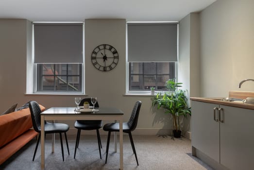 London, Liverpool - Oct 07, 2023 - Comfortable in living room of small apartment with table and chairs, sofa, sink and see the outside view through the windows. Real estate rent and home staging, Interior design, Space for text, Selective focus.