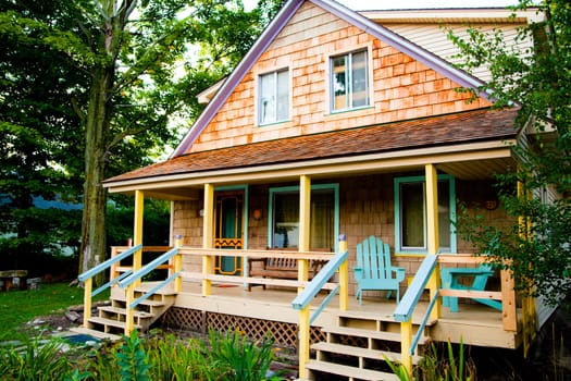 Charming two-story wooden house with warm cedar shingles and a inviting porch, surrounded by lush greenery in Empire, Michigan.