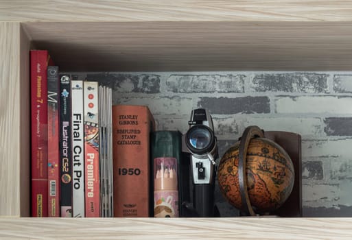 Bangkok, Thailand - jul 28, 2022 - Various books, Movie camera 8mm, Replica globe and Pencils on wooden shelf. Space for text, Selective focus.