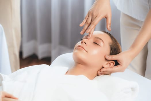 Caucasian woman enjoying relaxing anti-stress head massage and pampering facial beauty skin recreation leisure in dayspa modern light ambient at luxury resort or hotel spa salon. Quiescent