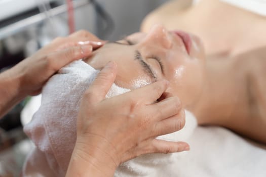 Beautiful caucasian woman lying on spa bed during having facial massage by professional hands at modern spa salon surrounded by beauty electrical equipment or medical equipment. Close up. Tranquility