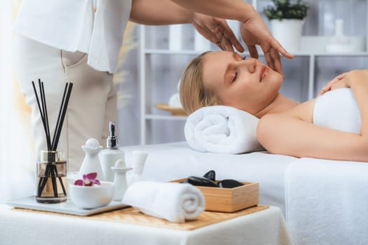 Caucasian woman enjoying relaxing anti-stress head massage and pampering facial beauty skin recreation leisure in dayspa modern light ambient at luxury resort or hotel spa salon. Quiescent