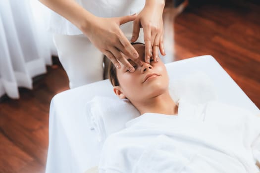 Caucasian woman enjoying relaxing anti-stress head massage and pampering facial beauty skin recreation leisure in dayspa modern light ambient at luxury resort or hotel spa salon. Quiescent