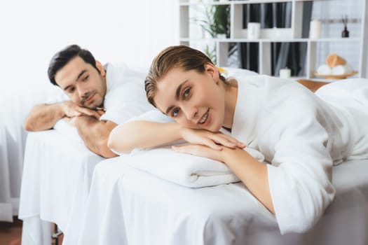 Caucasian couple customer enjoying relaxing anti-stress spa massage and pampering with beauty skin recreation leisure in day light ambient salon spa at luxury resort or hotel. Quiescent