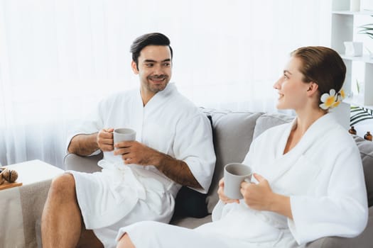 Beauty or body treatment spa salon vacation lifestyle concept with couple wearing bathrobe relaxing with drinks in luxurious hotel spa or resort room. Vacation and leisure relaxation. Quiescent