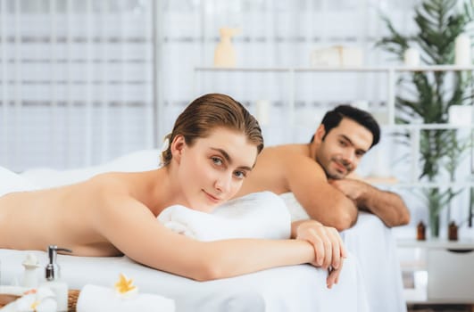 Blissful couple customer having exfoliation treatment in luxury spa salon with warmth candle light ambient. Salt scrub beauty treatment in health spa body scrub. Quiescent