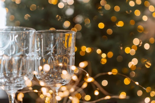 Champagne glasses, New Year decor. New Year's festive setting, family holidays.Two glasses of champagne are on the table against the background of New Year's decorated tree