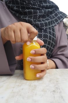 women holding a bottle of orange juice trying to remove the bottle cap .