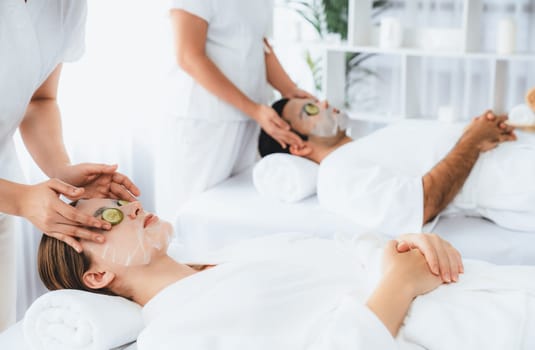 Serene daylight ambiance of spa salon, couple customer indulges in rejuvenating with luxurious cucumber facial mask. Facial skincare treatment and beauty care concept. Quiescent