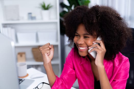 African woman talking with coworker or friend on the phone and looking at the screen with happy face. Achievement for promoting job position in the company with the good news life. Tastemaker.