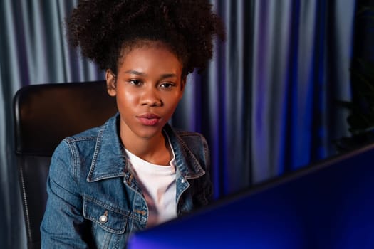 Young African American woman with surprise face, wearing blue jeans shirt and looking at final project document on laptop for planing next sequence. Concept of work at neat home place. Tastemaker.