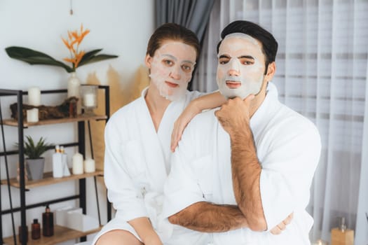 Serene modern daylight ambiance of spa salon, couple customer indulges in rejuvenating with facial skincare mask. Facial skin treatment and beauty cosmetology procedure for face. Quiescent