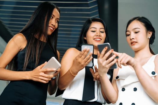 Three women friends having conversation while looking at mobile phone in their hands. Concept of social media, gossip news and online shopping. uds