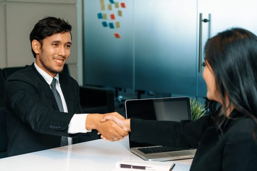 Business people agreement concept. Businessman and Asian businesswoman do handshake in the office. uds