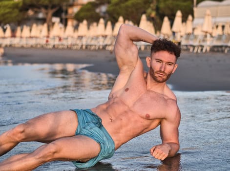 A muscular attractive man laying on the beach in a sunny morning