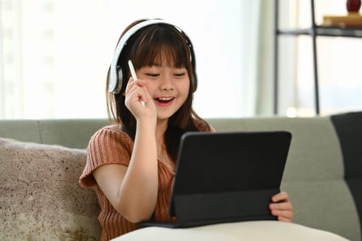 Shot of asian girl doing a school assignment on digital tablet at home