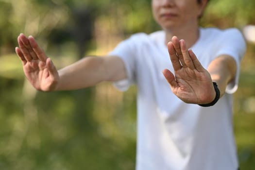 Peaceful middle age man practicing Tai Chi in a serene park. Healthy lifestyle concept