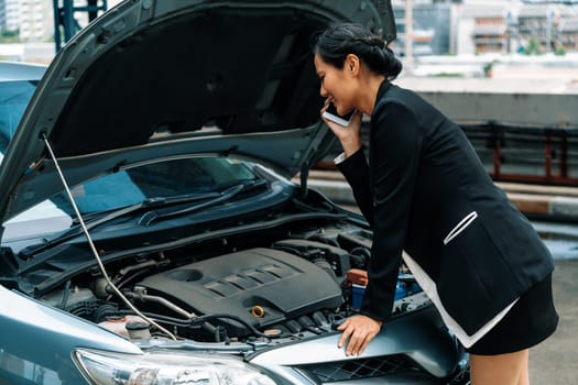 Young businesswoman whose car breakdown uses mobile phone to call for roadside assistance service. Travel and transportation vehicle problem. uds