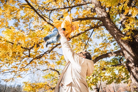 More, more,... dad, that's fun. Happy young father throws his cute little happy baby boy up in the air. Father's Day, Father and his son baby boy playing and hugging outdoors in nature in fall