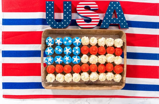 Flat lay. Arranging mini vanilla cupcakes in the shape of the American flag.