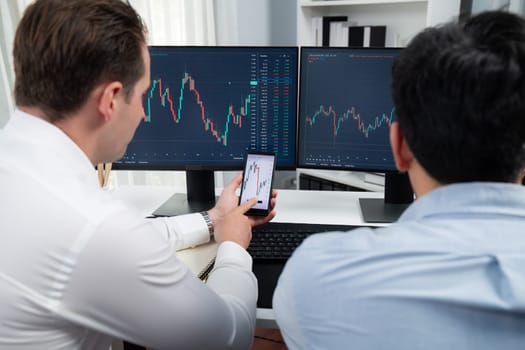 Stock exchange traders pointing lowest chart stage on dynamic graph with smartphone for investment, analyzing comparing with monitor and phone. Concept of discussing financial technology. Sellable.
