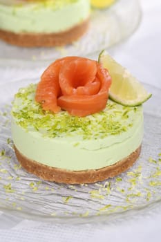 Timbale appetizer made from avocado, whipped with soft cheese cream and lime on short crust pastry with salmon. A great option for a holiday menu.