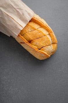 Freshly baked bread in a paper bag or package on a grey table, close-up. Copy space for text. The concept of organic farming food, no plastic.