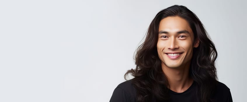 Elegant handsome smiling young male Asian guy with long hair, on white background, banner, copy space, portrait. Advertising of cosmetic products, spa treatments, shampoos and hair care products, dentistry and medicine, perfumes and cosmetology men
