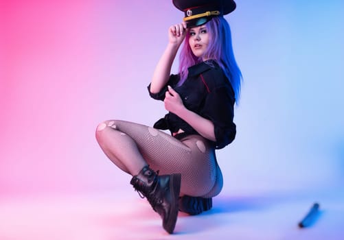 Sexy girl in police uniform posing in underwear with a police rubber baton in neon light on an empty background
