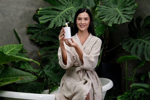 Tropical and exotic spa garden with bathtub in modern hotel or resort with woman in bathrobe holding beauty skincare product while enjoying leisure lush with greenery foliage background. Blithe