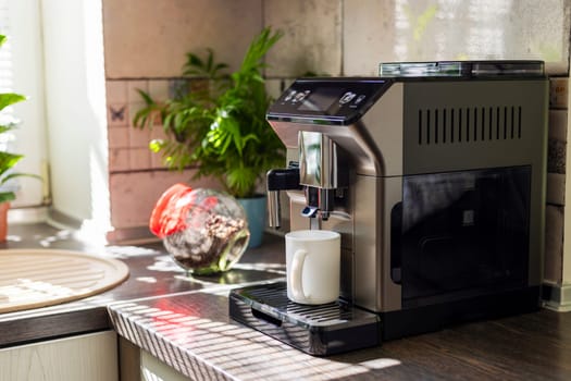 Modern electric coffee machine with cup on countertop in kitchen.